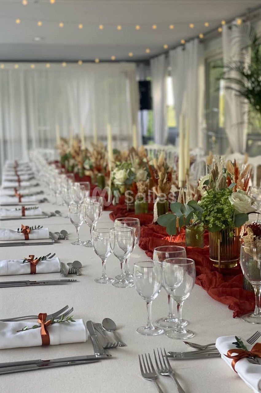 Table de réception élégamment dressée avec nappes blanches, décorations florales et couverts alignés.