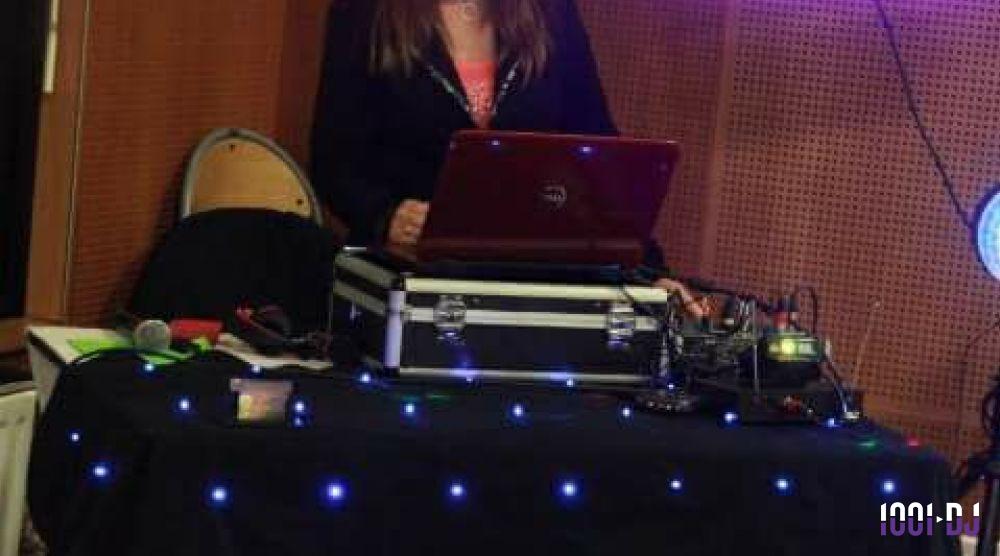 Une personne utilise un ordinateur portable posé sur une table équipée de matériel audio et éclairée par des lumières LED.