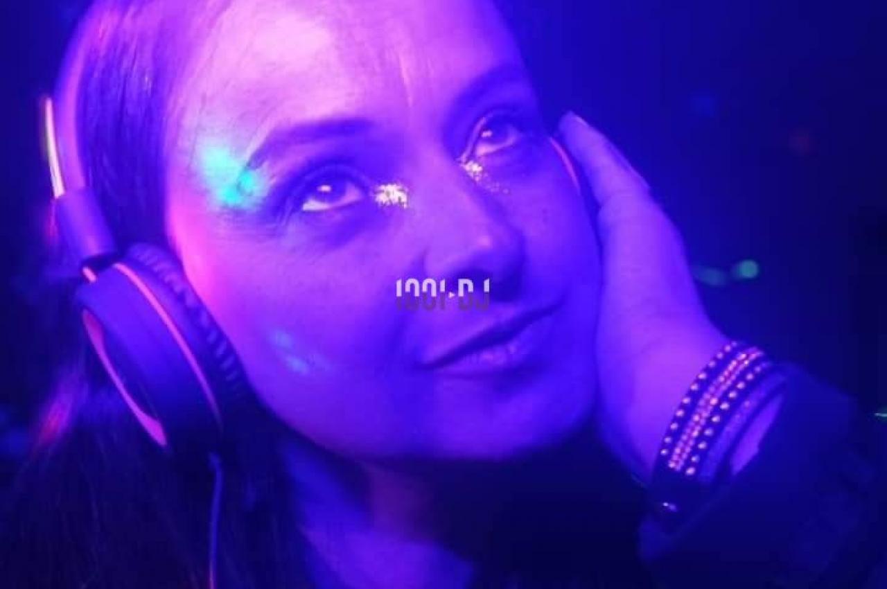 Femme portant un casque audio, éclairée par des lumières violettes et bleues dans une ambiance sombre.