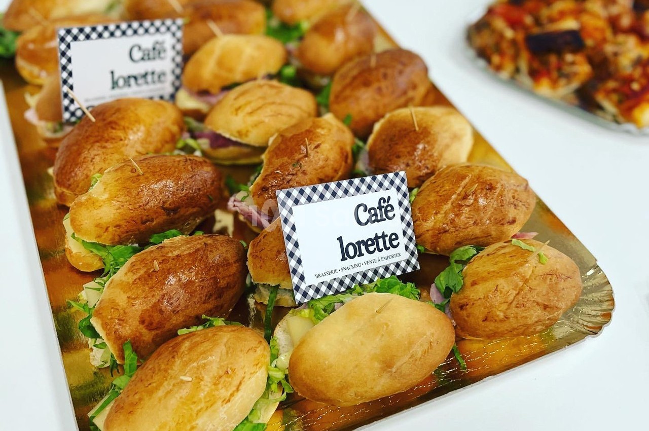 Plateau de petits sandwichs garnis de salade et de charcuterie, disposés sur un plateau doré.