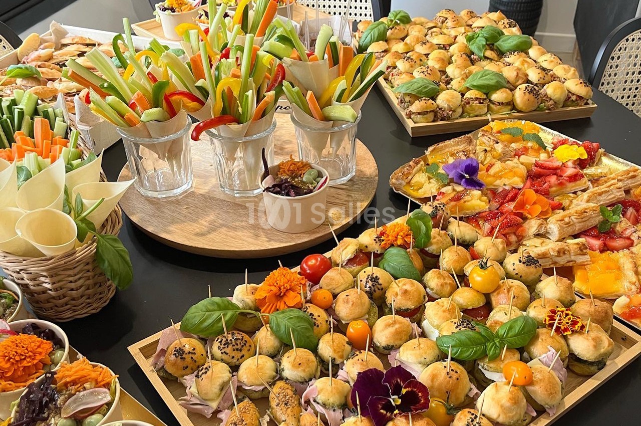 Buffet de pièces apéritives variées avec légumes croquants, mini-sandwichs, brochettes et tartes colorées.