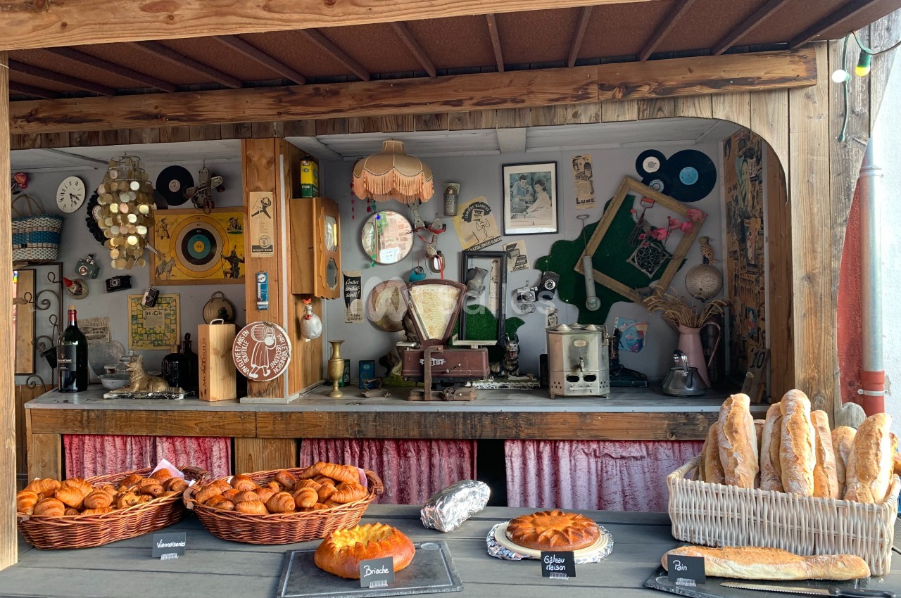 Stand en bois décoré de façon vintage, proposant des viennoiseries, pains et gâteaux exposés sur un comptoir.