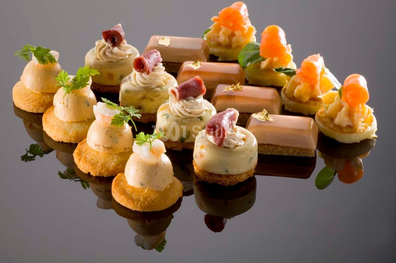 Assortiment de bouchées apéritives raffinées disposées sur une surface réfléchissante.