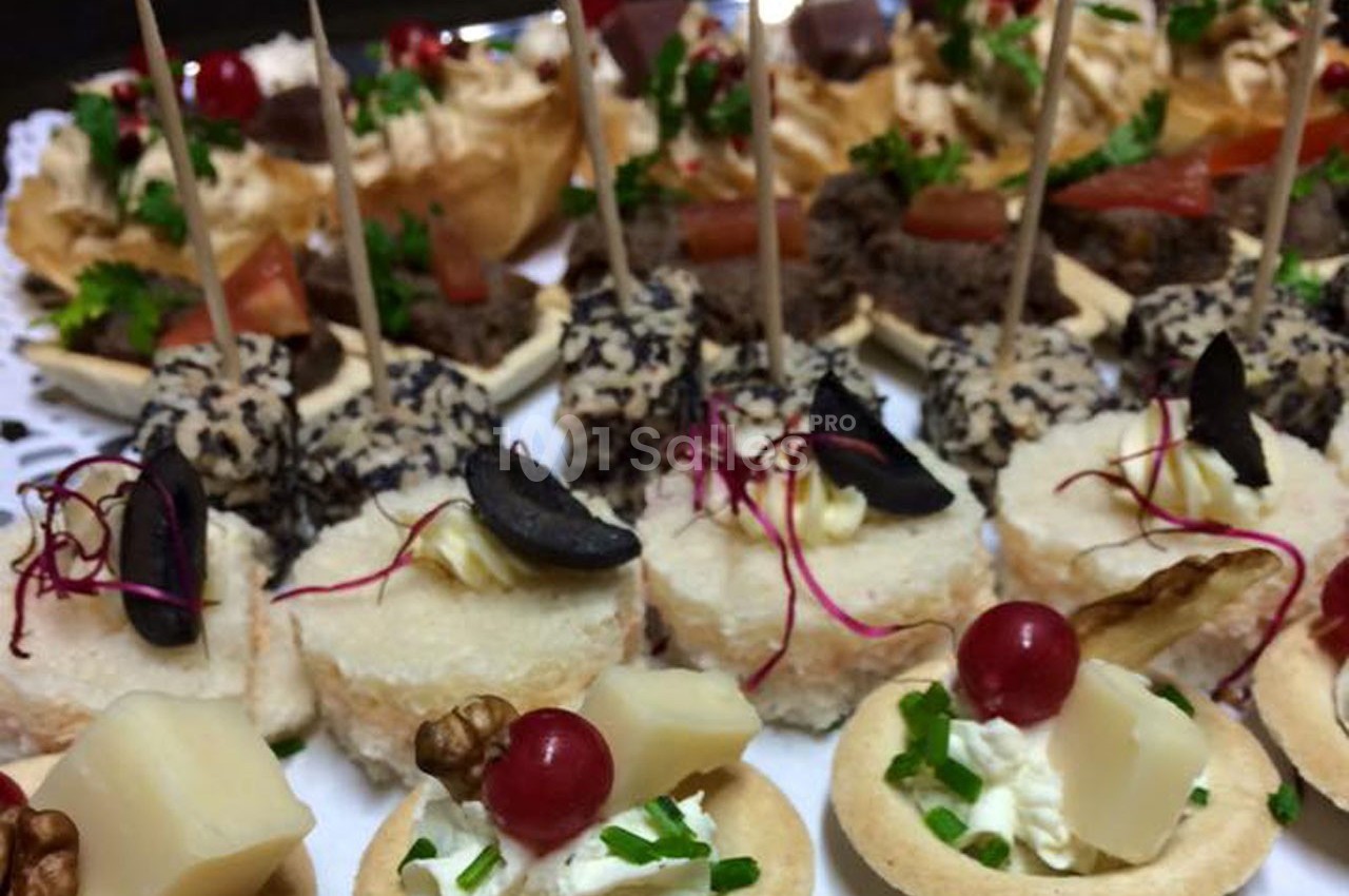 Plateau de canapés variés avec fromages, fruits, herbes fraîches et brochettes, présenté pour un buffet ou un apéritif.