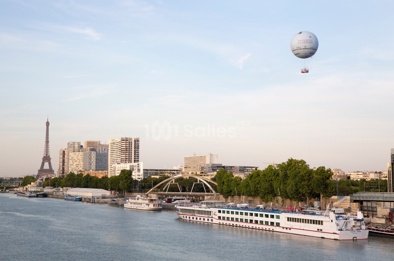 Vue de la Seine à Paris avec des péniches, la tour Eiffel en arrière-plan et un ballon captif dans le ciel.