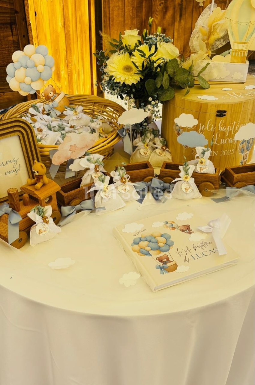 Table décorée pour une fête avec fleurs, ballons, cadeaux et éléments sur le thème des nuages et montgolfières.
