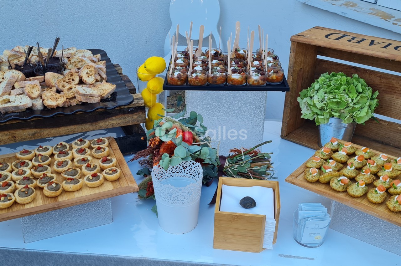 Buffet de bouchées apéritives variées disposées sur des plateaux en bois et en métal, décoré de plantes et d'éléments…