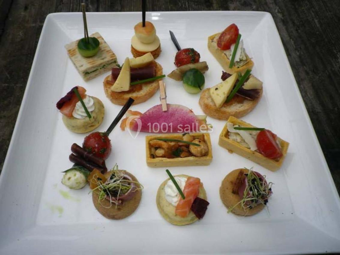 Assortiment de canapés variés disposés sur une assiette blanche, comprenant légumes, saumon et garnitures.