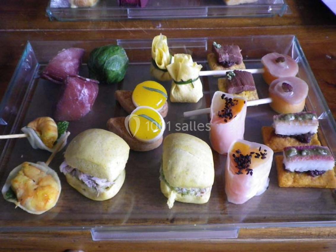 Plateau de bouchées apéritives variées comprenant sushis, mini-sandwichs et amuse-bouches colorés.