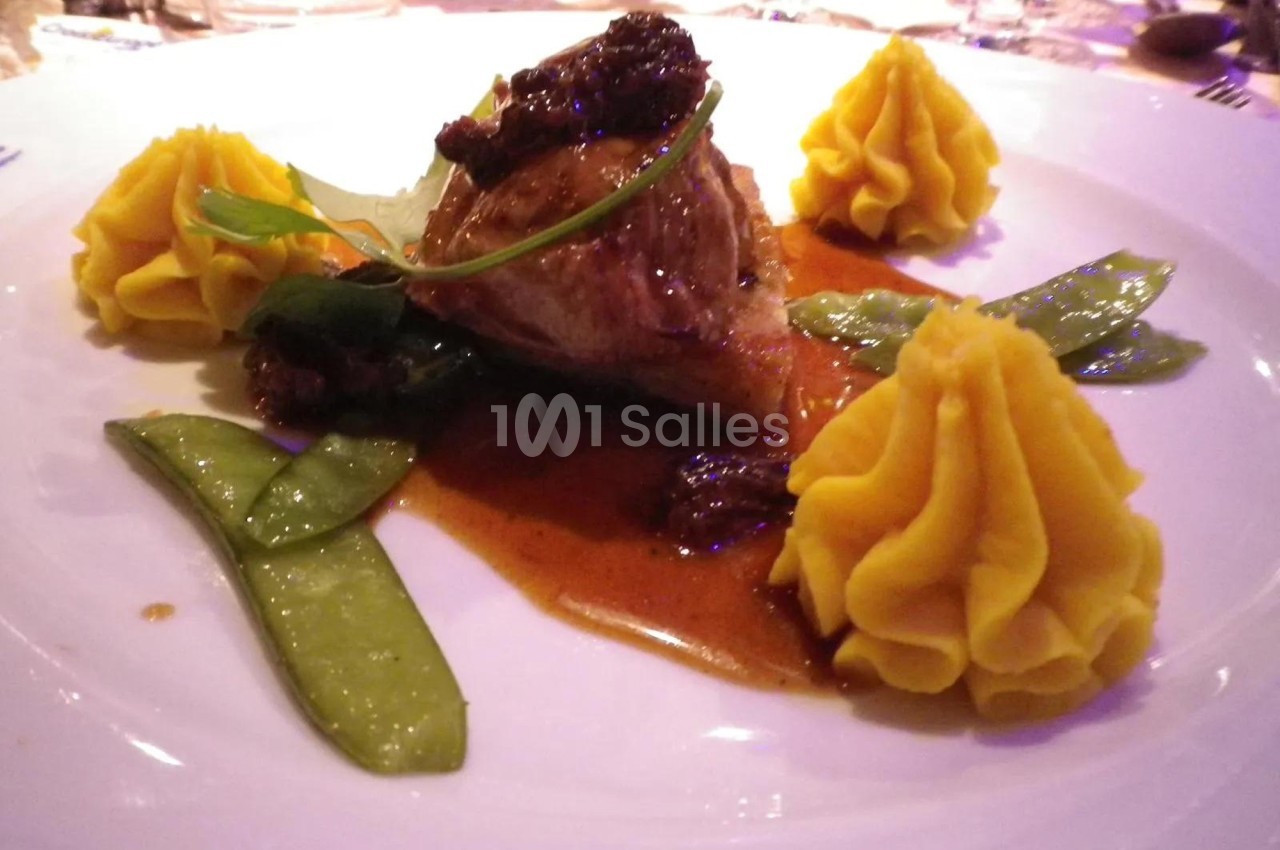 Assiette gastronomique avec viande en sauce, purée dressée en rosaces, pois gourmands et garniture végétale.