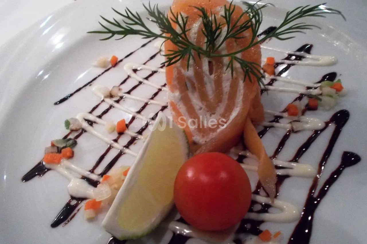 Assiette de saumon fumé roulé avec crème, décorée de sauce, légumes en dés, citron et tomate cerise.