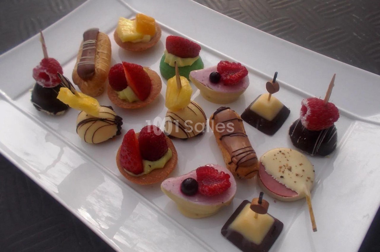 Assortiment de mignardises sucrées variées disposées sur un plateau blanc.