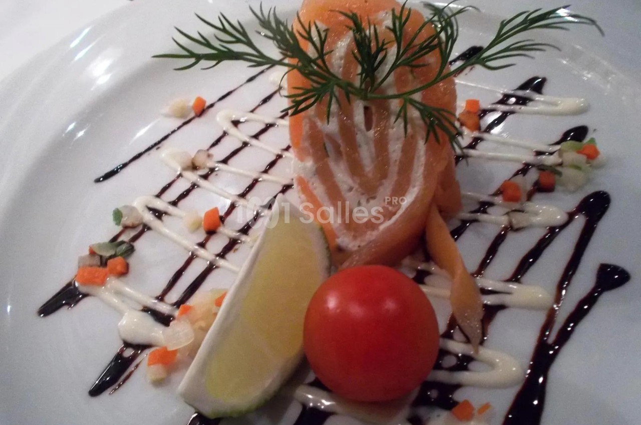 Assiette de saumon fumé roulé avec crème, décorée de sauce, légumes en dés, citron et tomate cerise.