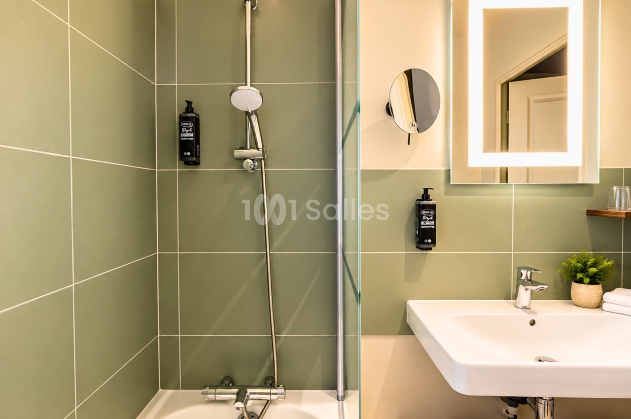 Salle de bains moderne aux carrelages vert menthe et beige, douche avec paroi vitrée et vasque blanche.