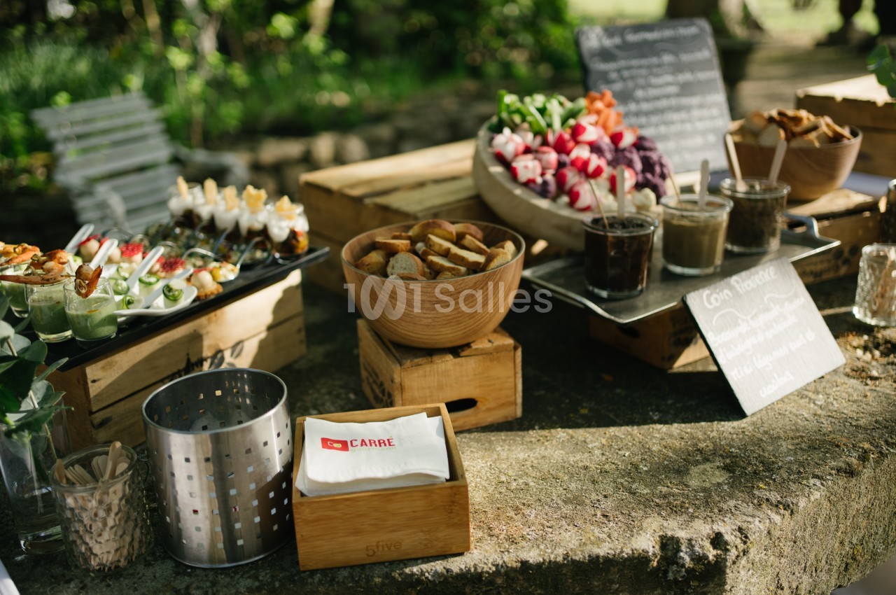 Buffet en plein air avec légumes frais, sauces, pains et serviettes disposés sur des caisses en bois.