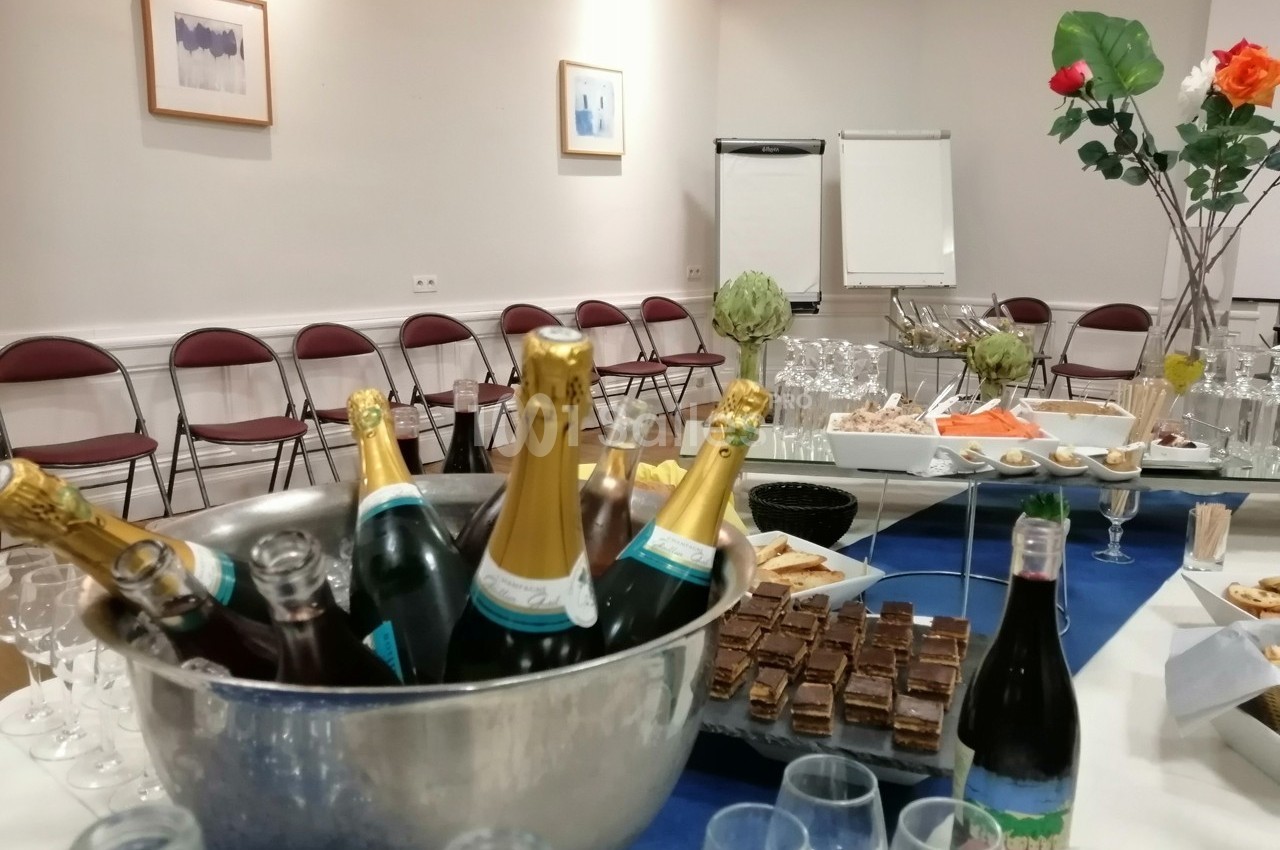 Table dressée pour un buffet avec bouteilles de champagne, verrines, desserts et chaises alignées en arrière-plan.
