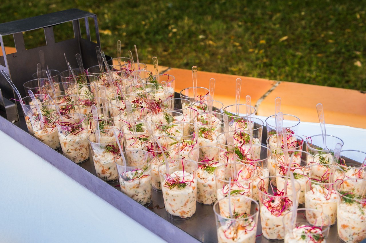 Verrines de salade garnies de radis et herbes fraîches, disposées sur un plateau en extérieur.