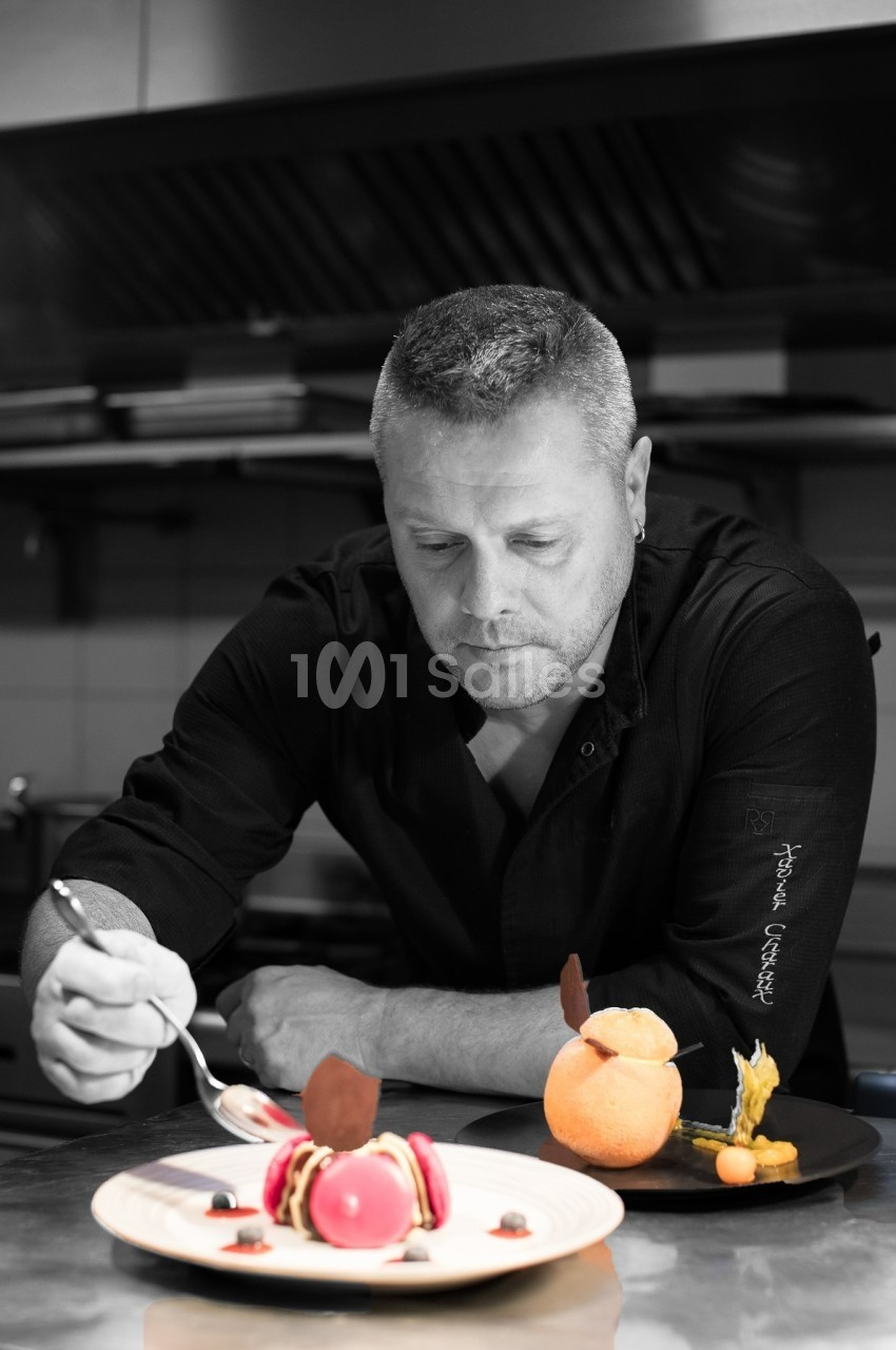Un chef pâtissier décore un dessert raffiné dans une cuisine professionnelle.