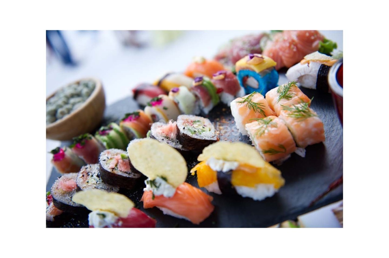 Assortiment de sushis variés présentés sur une ardoise, avec des garnitures colorées et des détails raffinés.