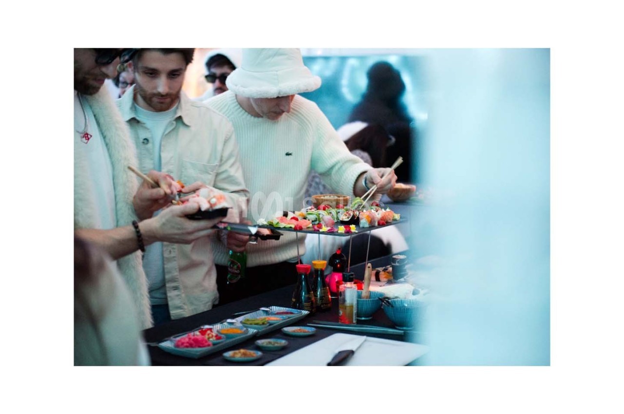 Des personnes se servent de sushis et d'accompagnements sur un buffet dans un cadre convivial.