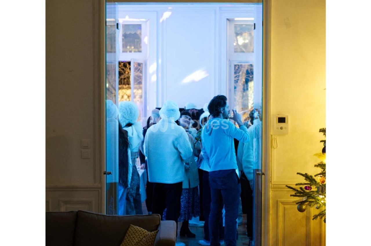 Groupe de personnes en vêtements d'hiver rassemblées dans une pièce éclairée par une lumière bleutée.