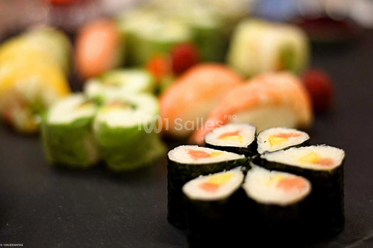 Assortiment de sushis et makis variés disposés sur une assiette sombre.