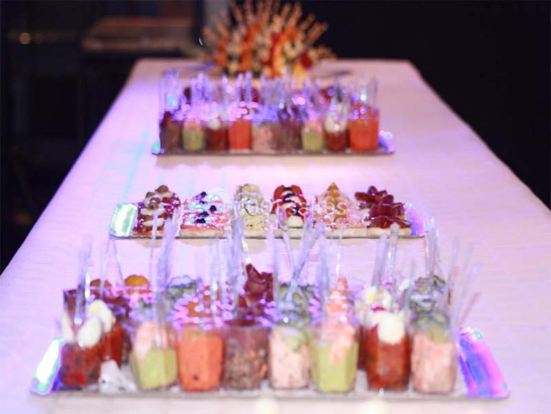 Plateaux de verrines colorées et apéritifs disposés sur une table blanche lors d'un buffet.