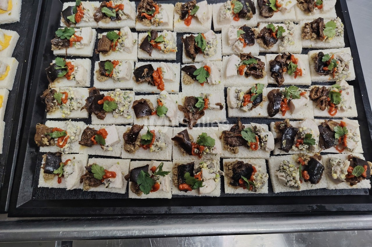 Plateau de canapés variés sur pain blanc, garnis de légumes, herbes fraîches et condiments colorés.