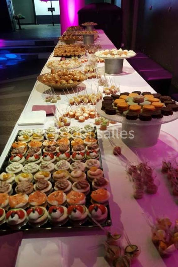 Table garnie de desserts variés, incluant cupcakes, verrines et pâtisseries, présentée dans un cadre événementiel.