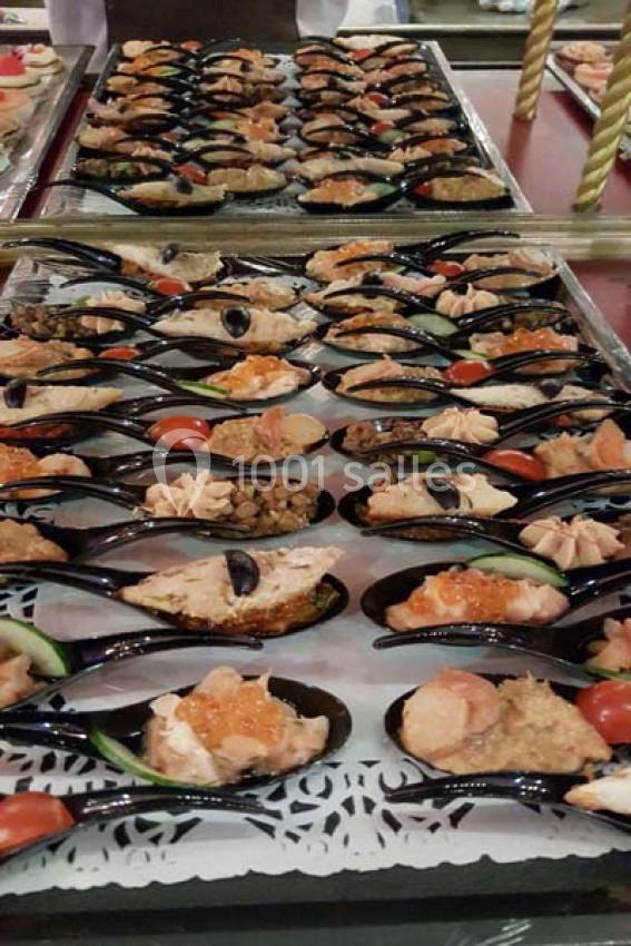 Plateau de moules garnies de diverses préparations culinaires, disposées sur un lit de dentelle blanche.