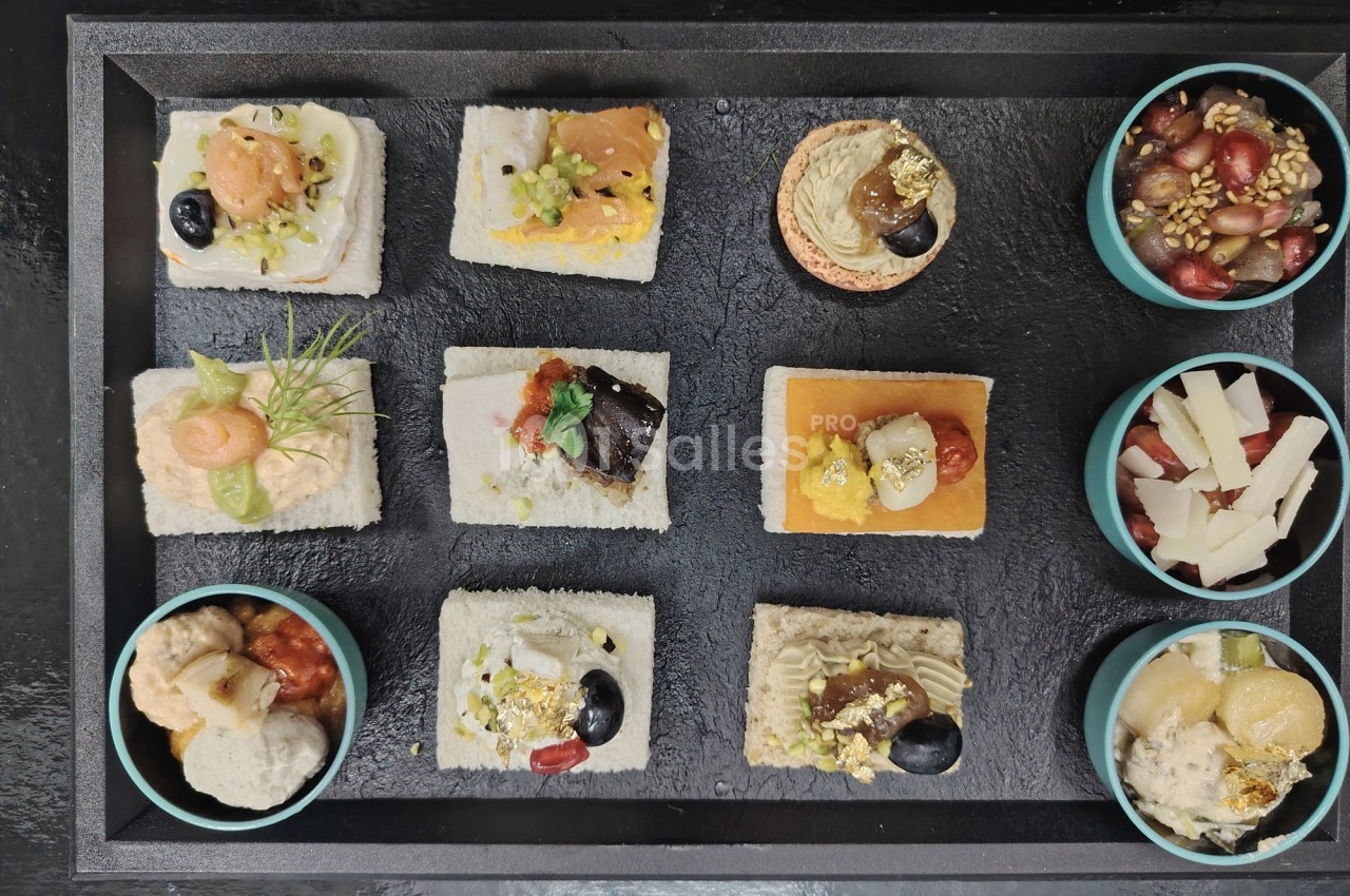 Plateau de canapés variés avec garnitures colorées et bols d'accompagnements, présenté sur une surface noire.