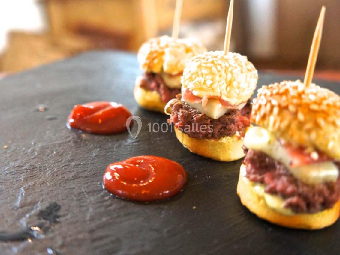Mini-burgers au bœuf avec fromage fondant, servis sur une ardoise avec des touches de sauce ketchup.