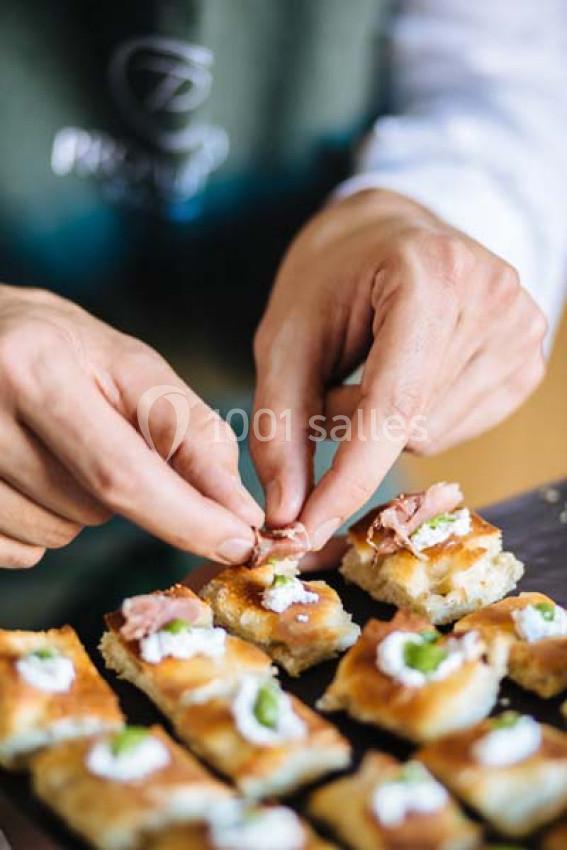 Un chef dispose délicatement des garnitures sur des bouchées apéritives sur un plateau.
