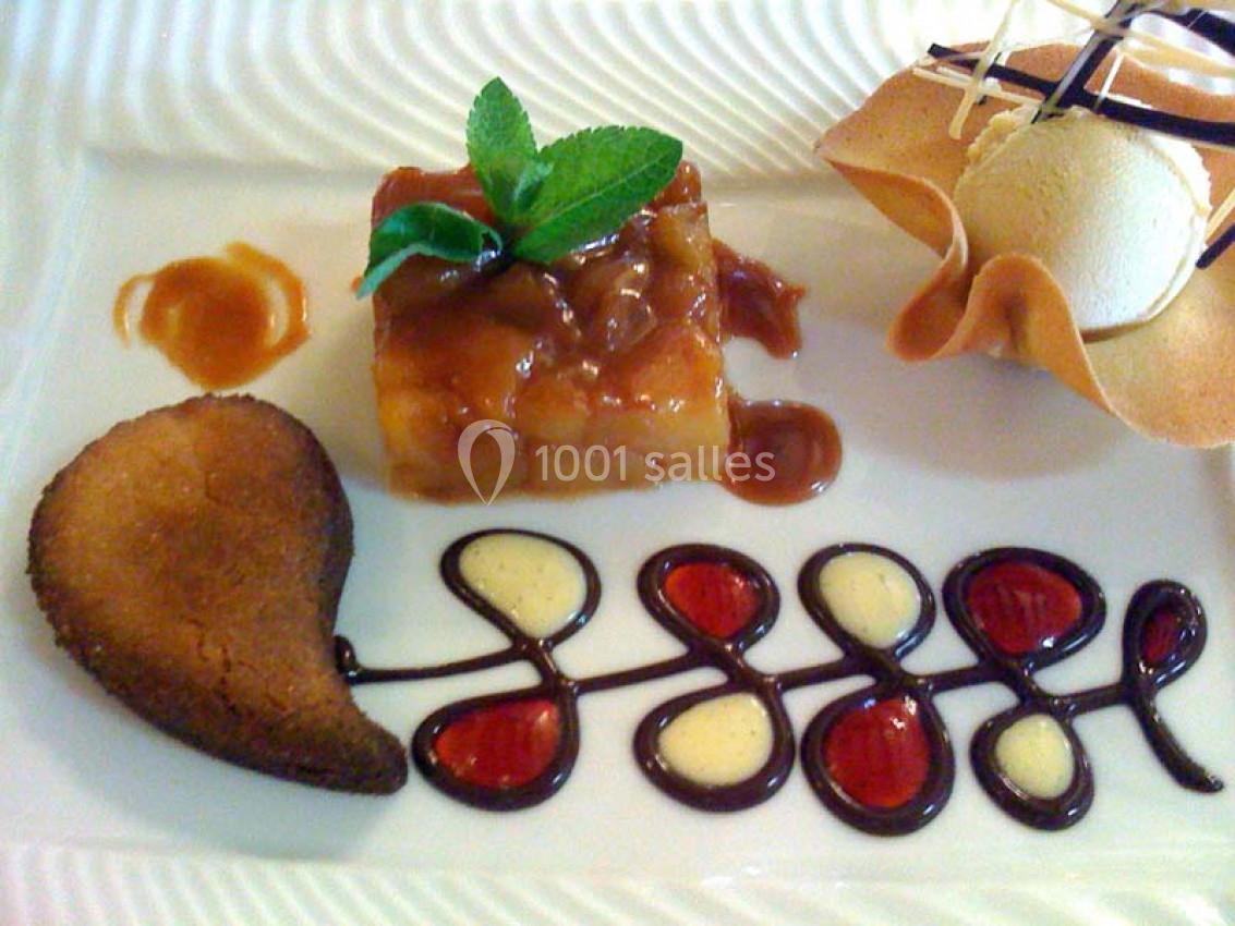 Dessert raffiné composé d'un gâteau caramélisé, d'une boule de glace, d'un biscuit et d'une décoration en sauce.