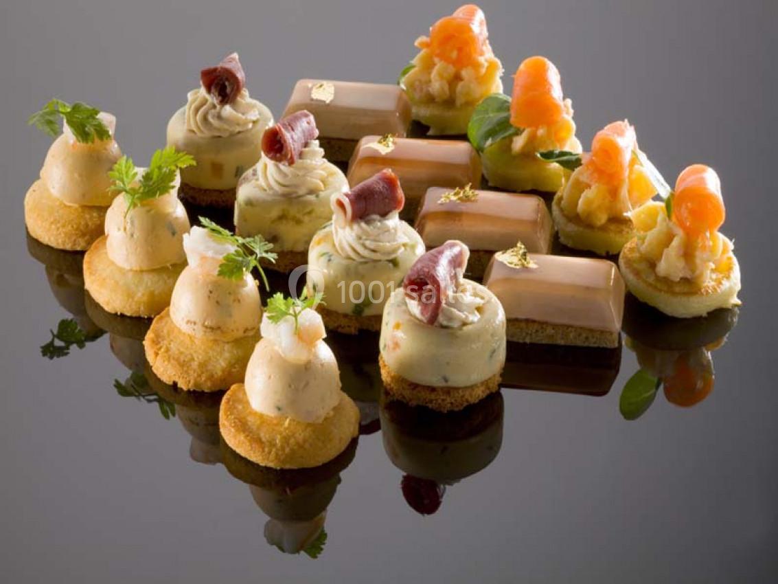 Assortiment de bouchées salées élégamment présentées sur une surface réfléchissante.