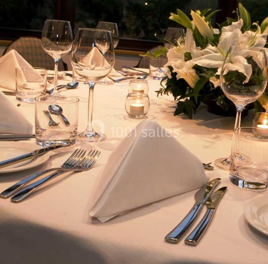 Table élégamment dressée avec serviettes pliées, couverts brillants, verres à vin et centre de table floral.