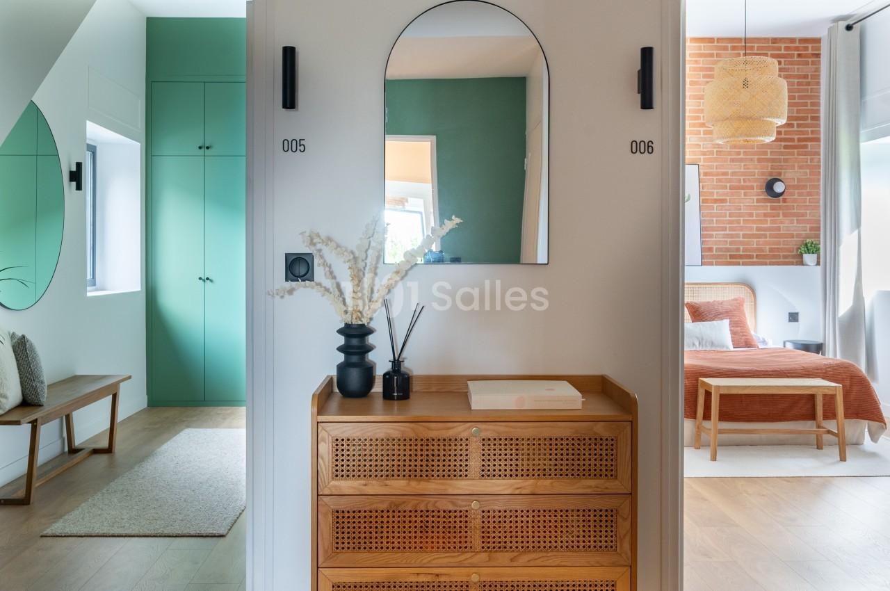 Meuble en bois avec miroir au mur, encadré par deux portes numérotées, dans un intérieur lumineux et moderne.