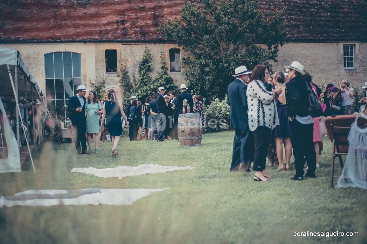 Groupe de personnes discutant dans un jardin devant un bâtiment ancien, lors d'un événement en plein air.