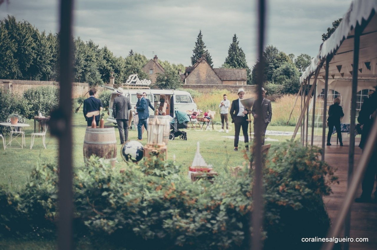 Des personnes discutent dans un jardin lors d'un événement en plein air, avec des tables et un food truck en arrière-plan.