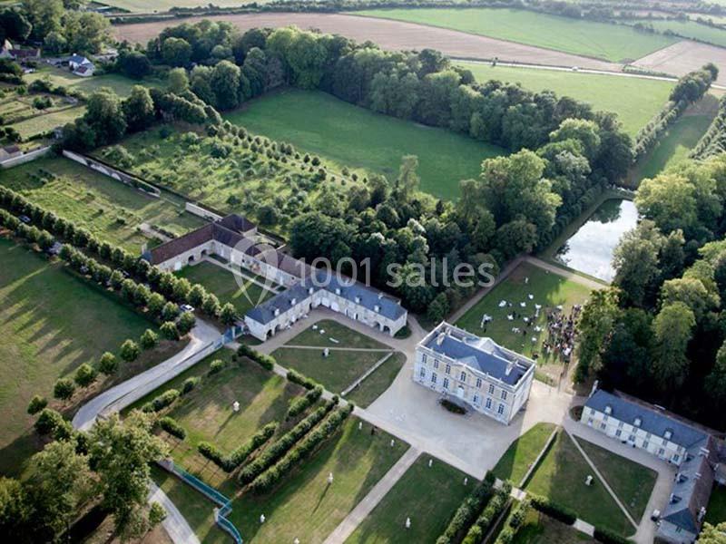 Vue aérienne d'un domaine avec un château, des bâtiments annexes, des jardins et des espaces verts environnants.
