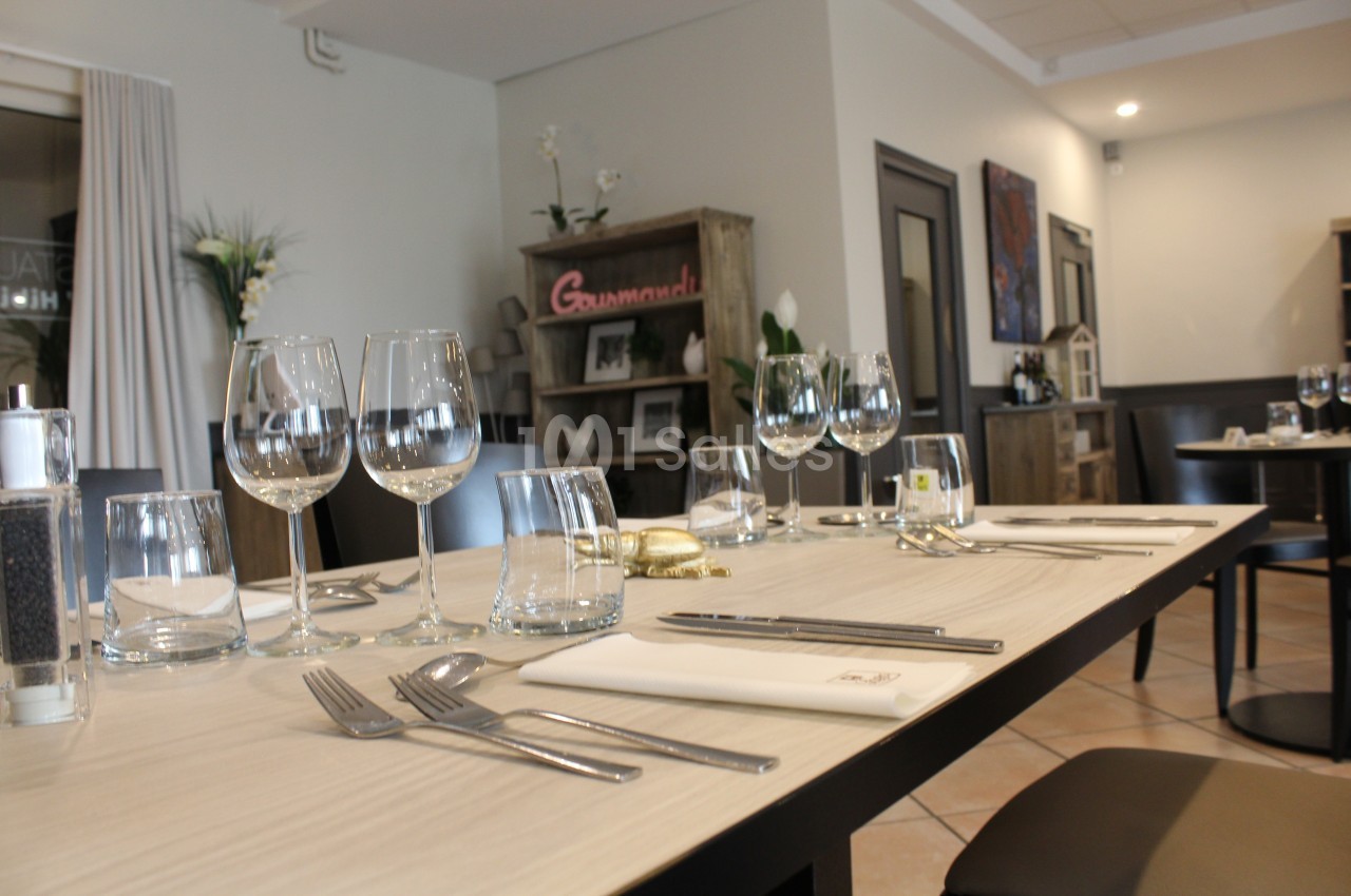 Table dressée avec élégance dans un restaurant, comprenant verres, couverts et serviettes sur une nappe claire.