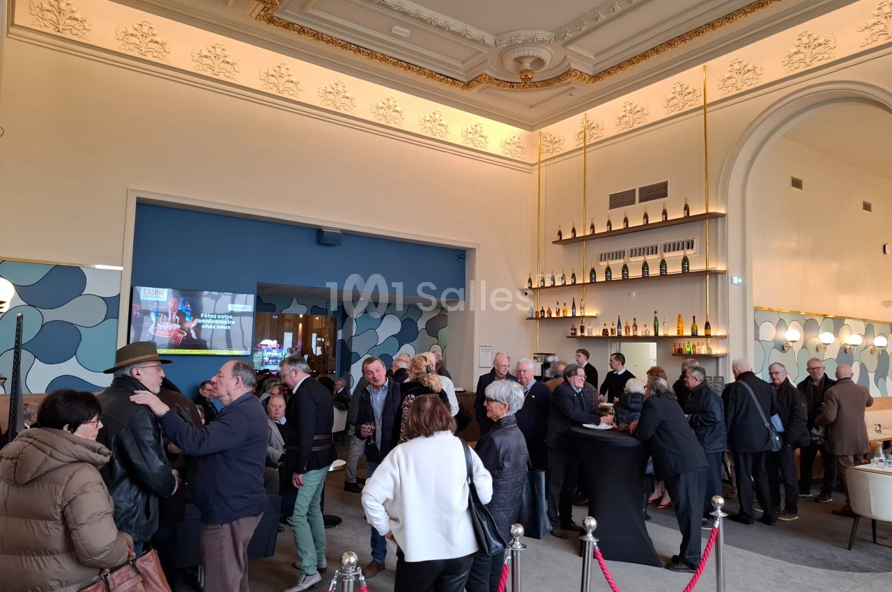 Groupe de personnes rassemblées dans un espace intérieur élégant avec un bar et une décoration lumineuse.