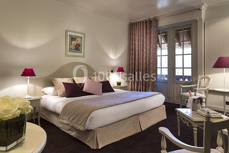 Chambre lumineuse avec lit double, coussins colorés, rideaux épais, table basse et balcon donnant sur l'extérieur.