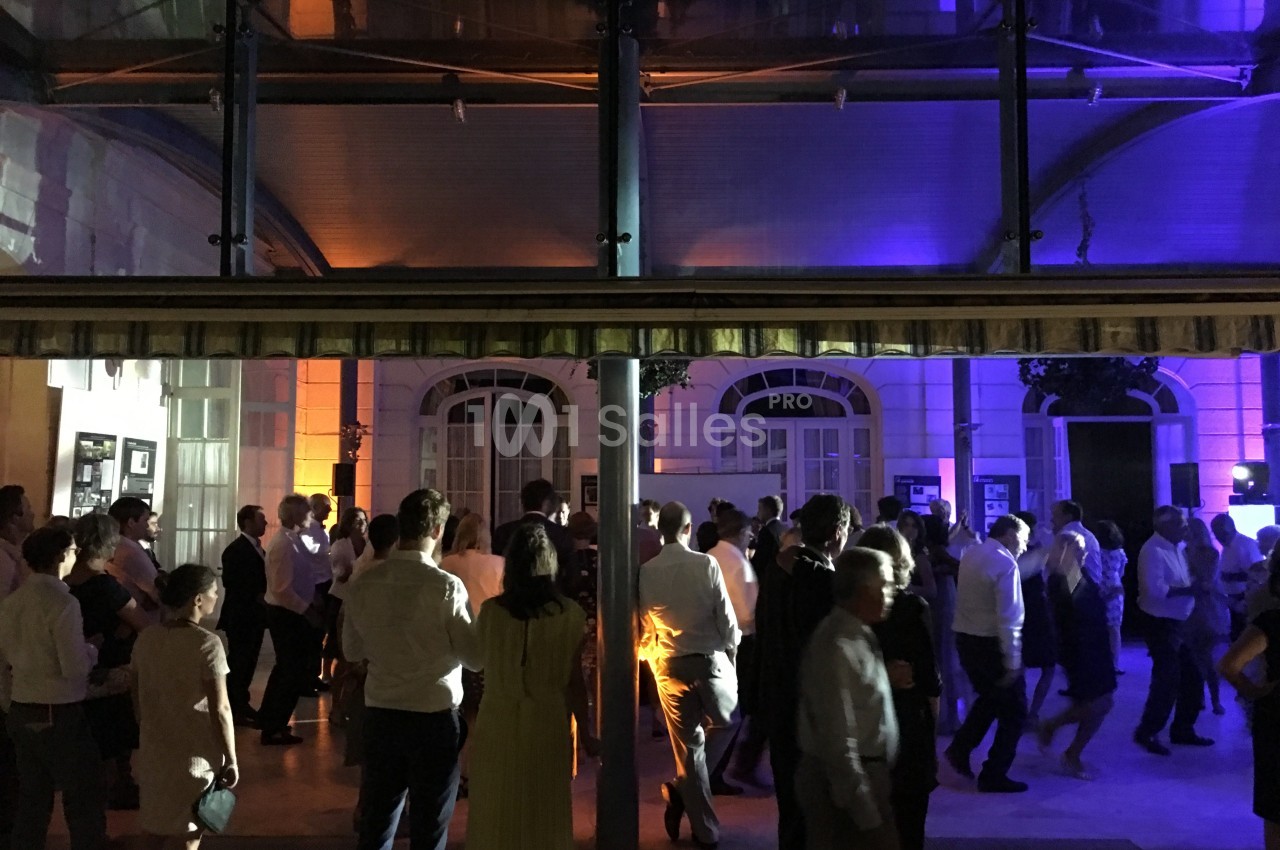 Groupe de personnes dansant et socialisant lors d'un événement nocturne dans un espace éclairé par des lumières colorées.