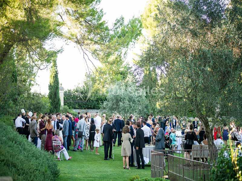 Groupe de personnes rassemblées dans un jardin verdoyant lors d'un événement en plein air.