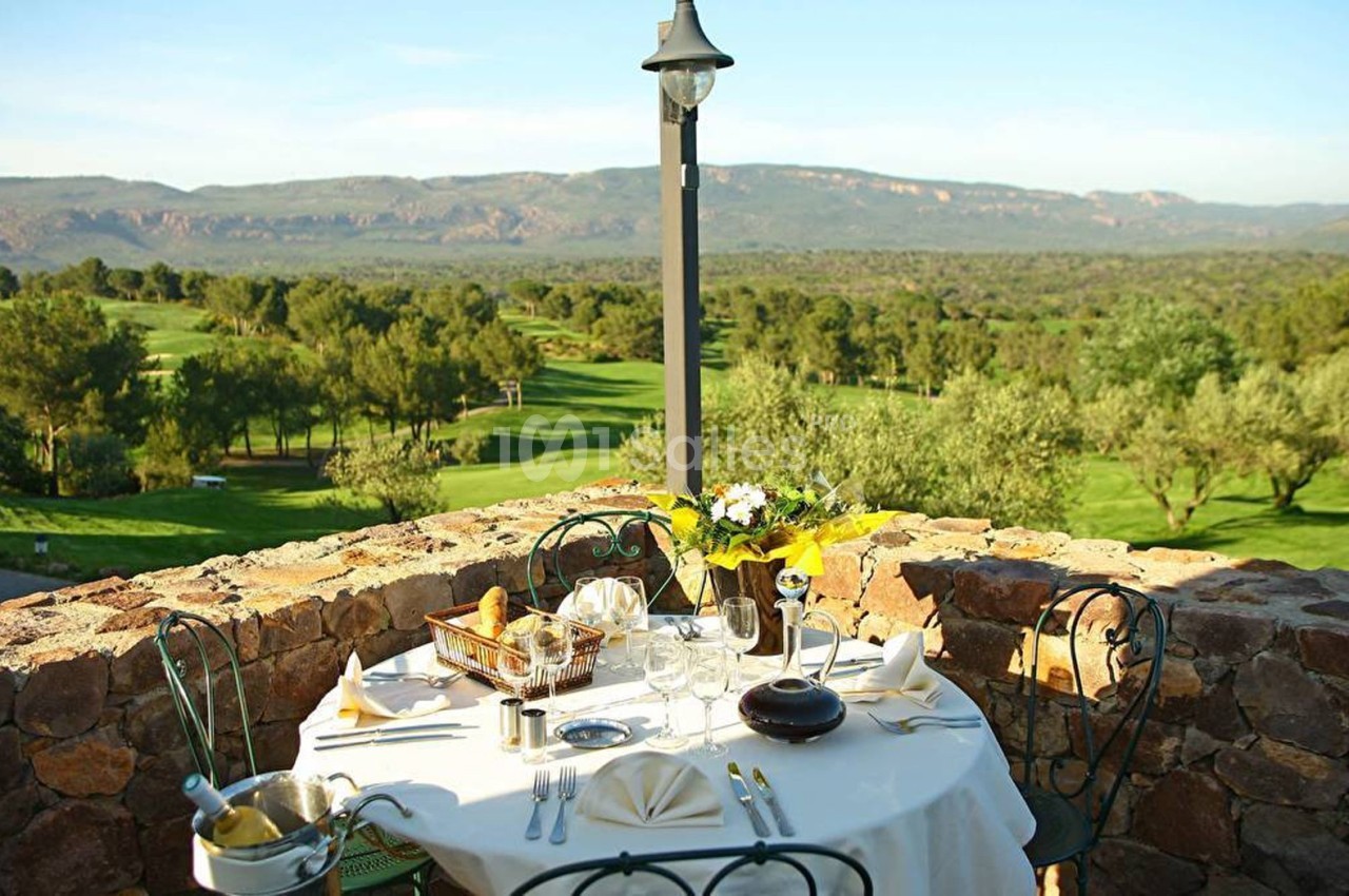 Table dressée en extérieur avec vue sur un paysage verdoyant, des collines et un terrain de golf au loin.