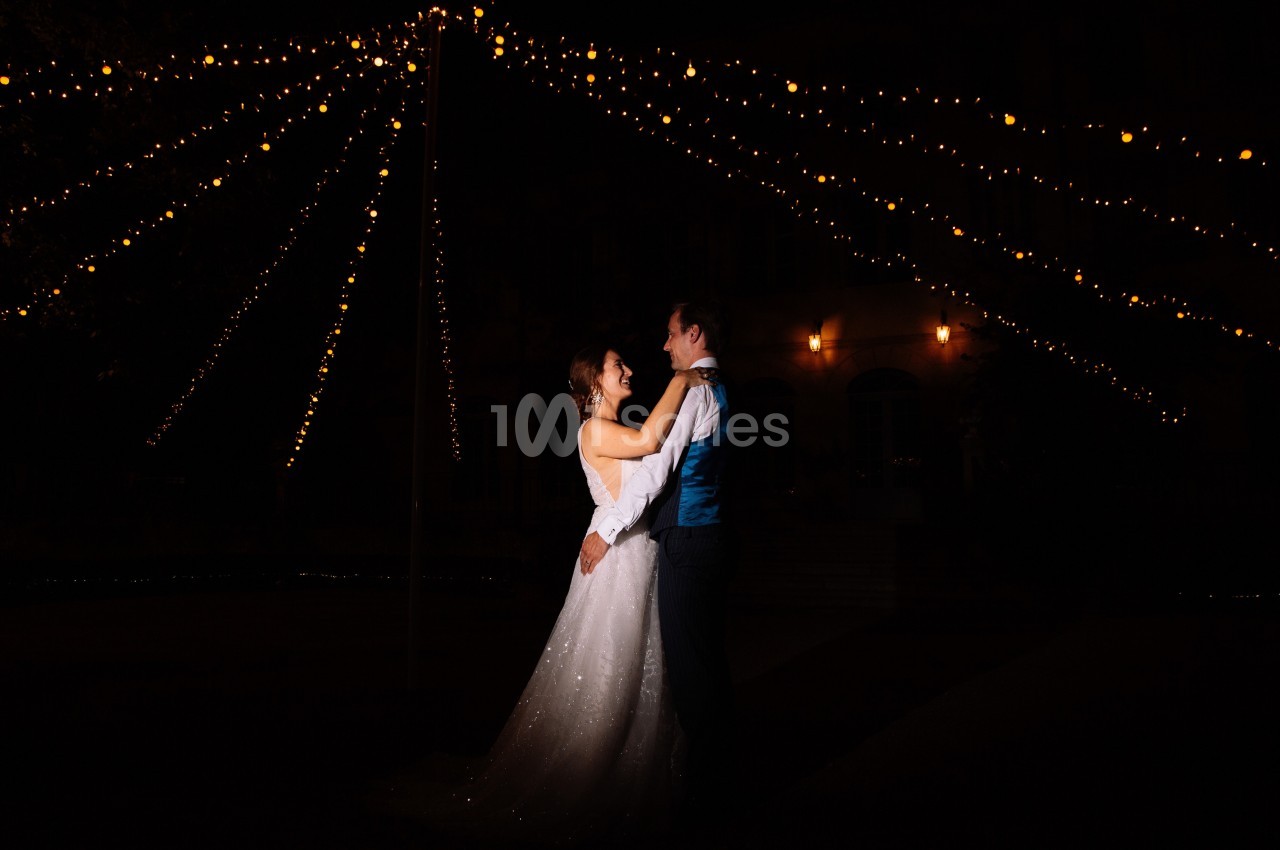 Un couple danse sous des guirlandes lumineuses dans un décor nocturne.