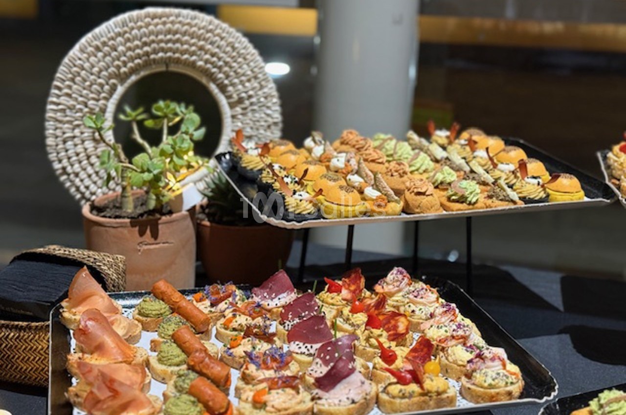 Plateaux de canapés variés avec garnitures colorées, présentés sur une table décorée de plantes et d'éléments naturels.