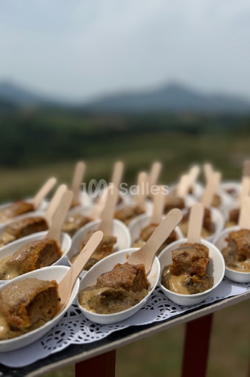 Portions individuelles de gâteau servies dans des cuillères blanches avec une sauce, présentées sur un plateau en extérieur.