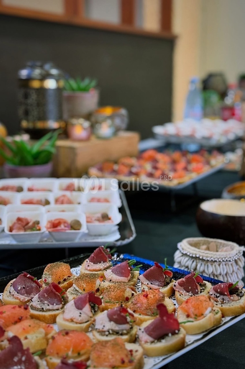 Plateau de canapés variés avec saumon, jambon et garnitures, présenté sur une table de buffet décorée.